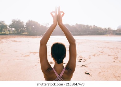 Back View Of Caucasian Woman In Sportive Top Gesturing With Hands Some Details During Holistic Healing At Seashore Coastline, Female Spending Weekend Daytime For Training Brain During Meditation