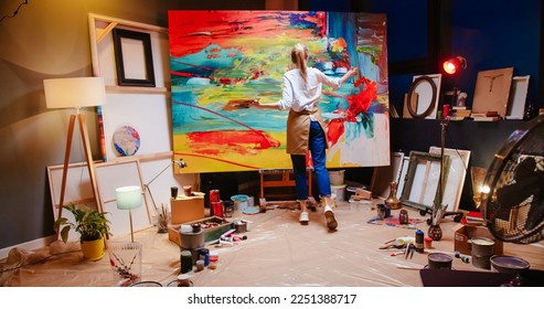 Back view of Caucasian young talented female painter working in cozy workshop in evening emotionally drawing on big canvas colorful abstract painting. Artwork, contemporary oil painting, work concept - Powered by Shutterstock