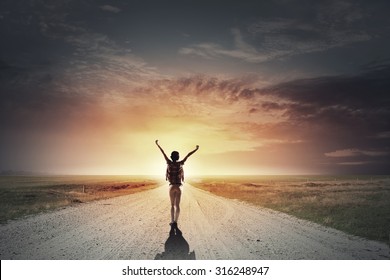 Back View Of Cheerful Woman With Hands Up Facing Sunrise