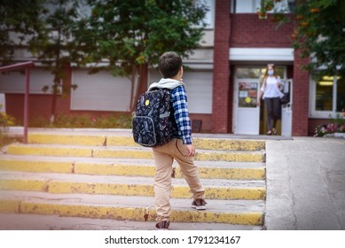 Back View Child Boy With Bag Goes To Elementary School And Masked Woman Comes Out Of The Door. Copytext