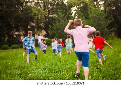 Back view of children running on green grass