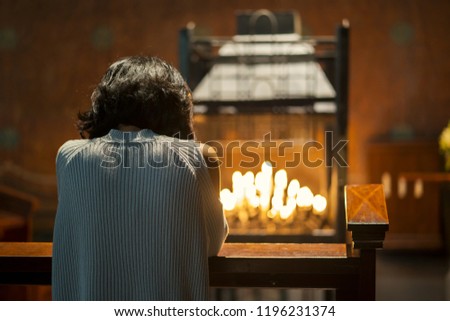 Back view of a Christian woman sitting in the church while praying to the GOD