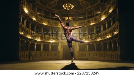 Back View Cinematic Shot of Athletic Man Dancing and Rehearsing Pirouettes on Classic Theatre Stage with Dramatic Lighting. Graceful Classical Ballet Male Dancer Performing his Choreography