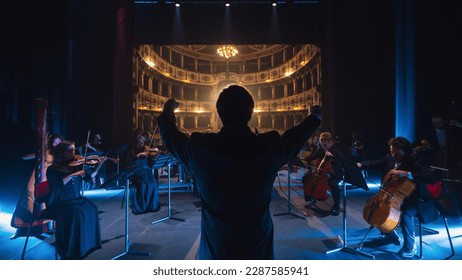 Back View Cinematic shot of Conductor Directing Symphony Orchestra with Performers Playing Violins, Cello and Trumpet on Classic Theatre with Curtain Stage During Music Concert - Shutterstock ID 2287585941