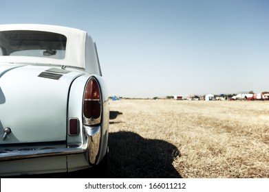 Back View Of A Classic Car Parked In A Field