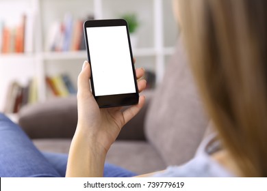 Back view close up of a woman hand using a smart phone with blank screen lying on a couch at home