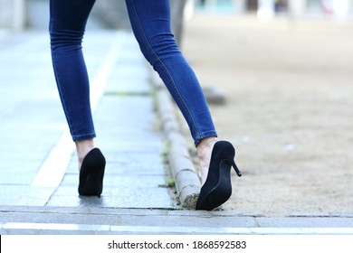 Back view close up of a woman legs with high heels stumbling in the street