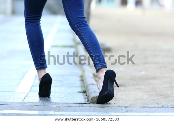 Back view close up of a woman legs with high heels\
stumbling in the street
