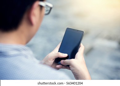 Back View Of A Close Up Of Young Man Using Mobile Smart Phone.