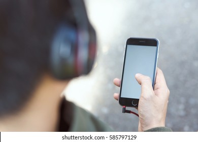 Back View Of A Close Up Of Young Man Using Earphone  Mobile Smart Phone.