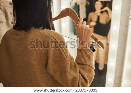 Back view closeup of insecure young woman trying on clothes in dressing room, copy space