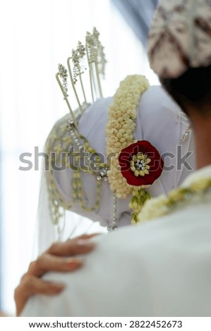  Back view close-up of a Javanese bride headpiece decorated with jasmine flower garland, traditional hairpins, and veil.
