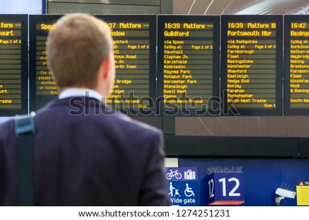 Back view of a commuter checking timetables at Waterloo station in London