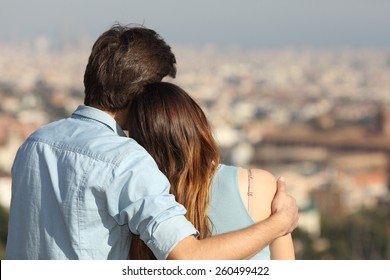 Back view of a couple dating in love hugging and looking the city in a sunny day