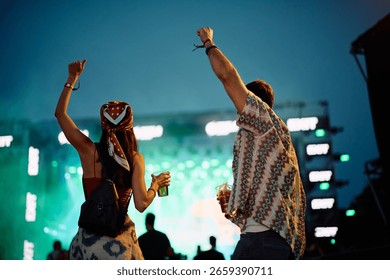 Back view of couple having fun at open air music concert at night.