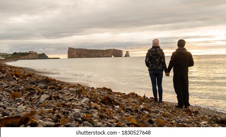 Back View Of A Couple Holding Hands And Admiring The Percé Rock, In Canada