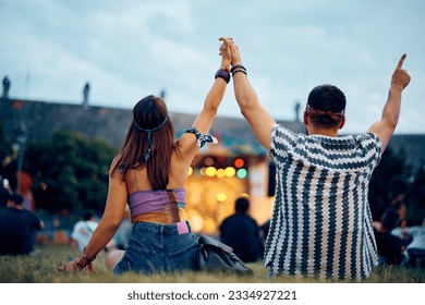 Back view of couple with raised arms listening music at open air concert. - Powered by Shutterstock