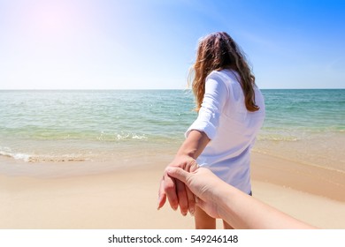 Back view of a couple taking a walk holding hands on the beach