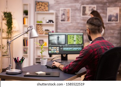 Back view of creative filmmaker working on a movie on laptop. Girlfriend in the background. - Shutterstock ID 1585522519
