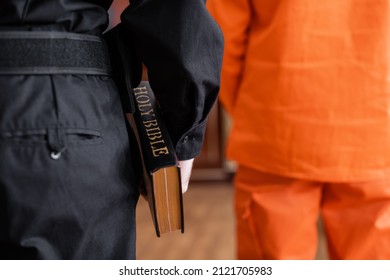 back view of cropped bailiff holding bible while standing near accused man in court