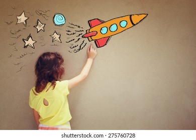 Back View Of Cute Kid (girl) Imagine Space Rocket With Set Of Infographics Over Textured Wall Background 