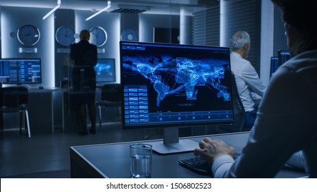 Back View Of The Cyber Security Officer Working On Personal Computer Showing Traffic Data Flow In The System Control Room Full Of Special Intelligence Agents.