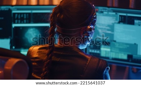 Back view of a Cyberpunk girl types on the keyboard. Multiple computer screen with strings of codes infront of her. Devloping codes for futuristic software. Neon lights in the background.