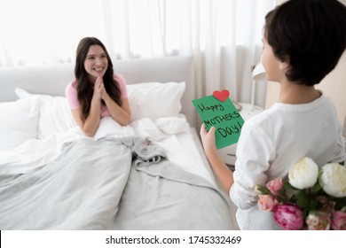 Back view of a dark-haired boy standing in front of his cheerful mother in a bedroom