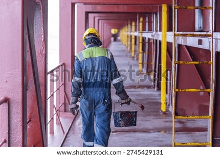 Back view of a deck crew member performing routine duties on the open deck during a sea voyage.