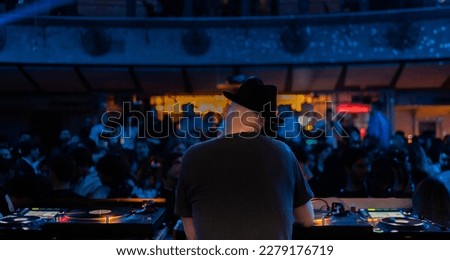 Back view of a deejay while mixing his tracks at the console during a concert in the disco