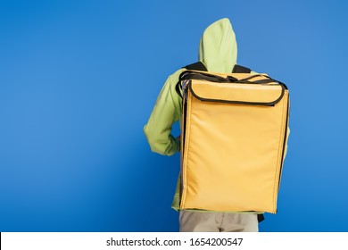 Back View Of Delivery Man Carrying Thermo Backpack On Blue Background