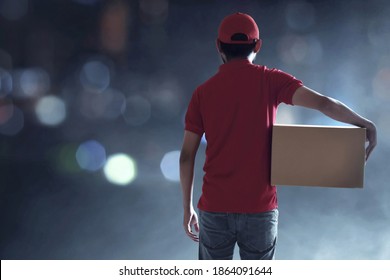 Back View Of Delivery Man Holding Cardboard Box