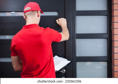 Back view of a delivery man knocking on the client's door
