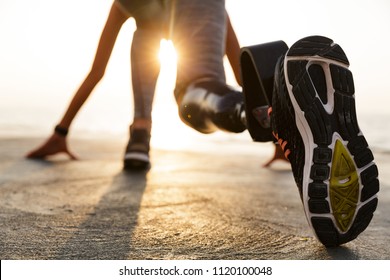 Back view of disabled athlete woman with prosthetic leg starting to run outdoor at the beach - Shutterstock ID 1120100048