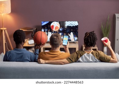 Back view at diverse group of friends watching basketball match at home and drinking beer - Powered by Shutterstock