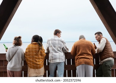 Back View At Diverse Group Young People Relaxing On Balcony During Party At Lake House