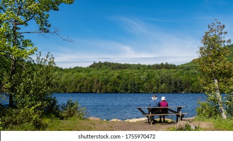 Back view of an elderly couple sitting in front of Lake Stukely, at the mont-Orford national park, Canada