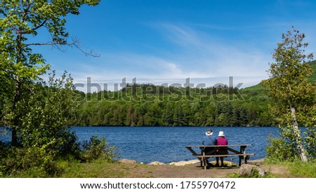 Back view of an elderly couple sitting in front of Lake Stukely, at the mont-Orford national park, Canada