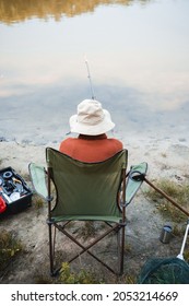 Back View Of Elderly Man Fishing Near Toolbox And Lake Outdoors