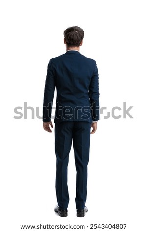 back view of elegant young man in navy blue suit standing in front of white background