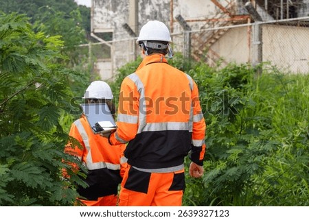 Back View of Engineers with Laptop Collaborating at Industrial Site with Storage Tanks, Team of Engineers Conducting Operations at Oil Storage Field Industrial Site