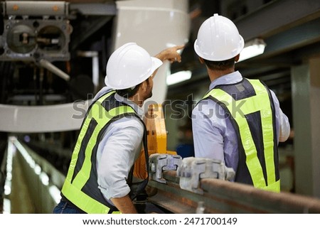 Back view engineers talking and looking at high-speed rail or train at construction site