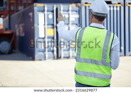 back view factory worker or engineer looking forward and pointing pose in containers warehouse storage