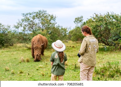 Back View Of Family On Safari Walking Close To  White Rhino