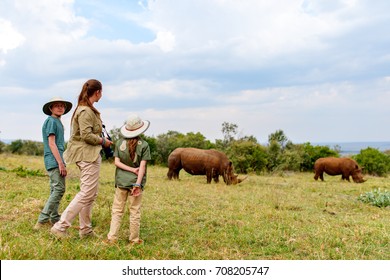 Back View Of Family On Safari Walking Close To  White Rhino