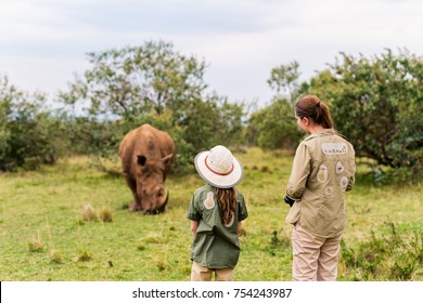 Back View Of Family On Safari Walking Close To  White Rhino