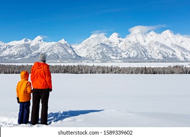 Back View Of Family Of Two, Father And Son, Enjoying Gorgeous View Of Teton Range In Grand Teton National Park, Wyoming, Usa At Winter