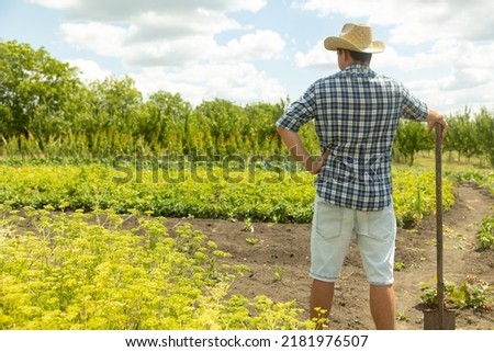 Back view of farmer man in a hat, with a shovel, who was about to dig a garden