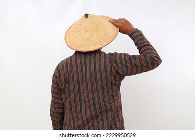 Back view of farmer standing while holding his hat. Isolated on white background