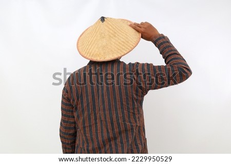 Back view of farmer standing while holding his hat. Isolated on white background